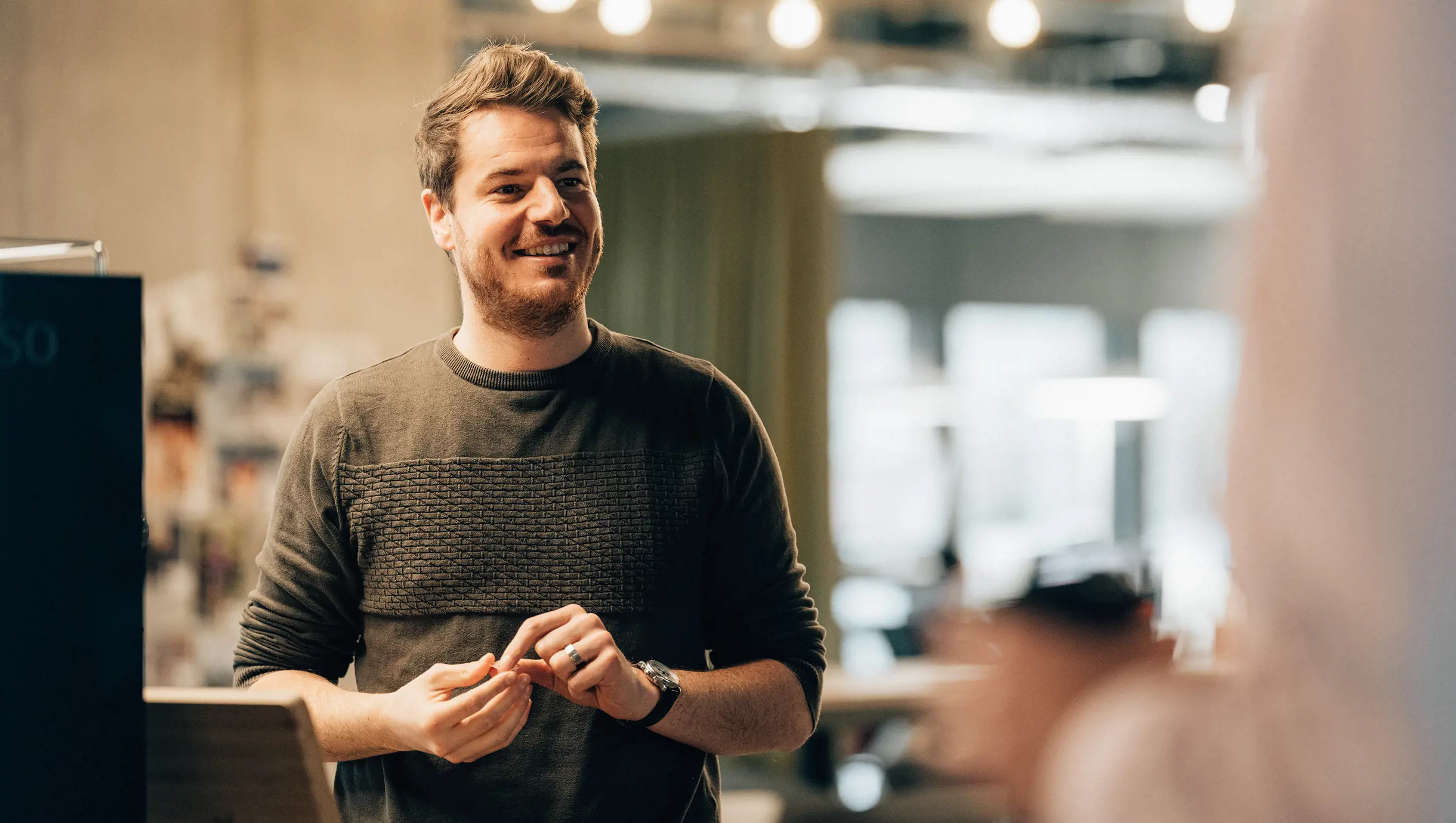 Männlicher Business Consultant  steht lachend vor Kaffeemaschine