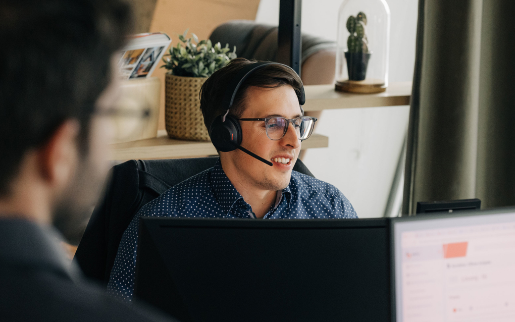 Mann am PC mit Headset bearbeitet Leads aus Marketing Kampagne