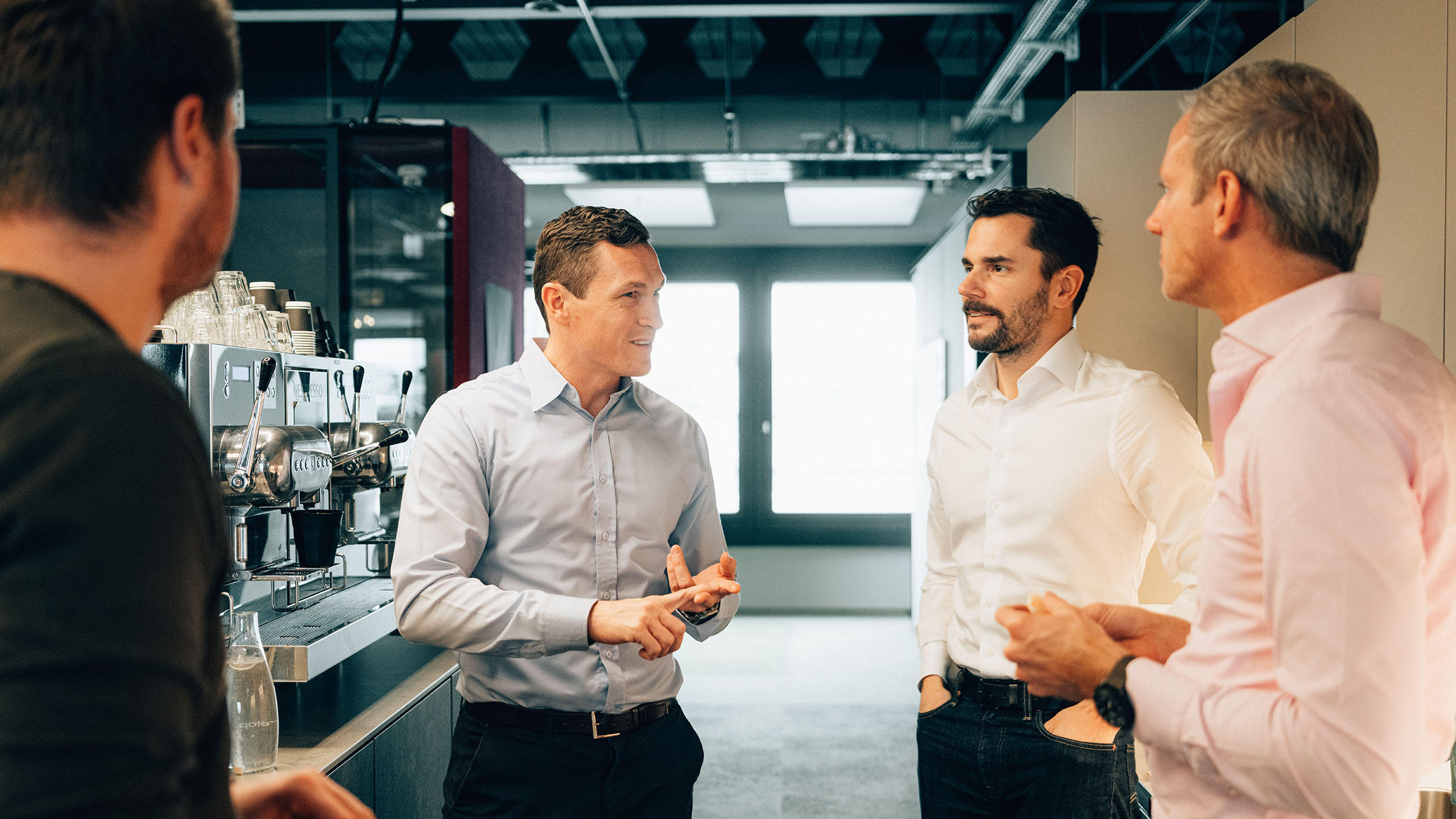 Besprechung vor Kaffeemaschine zu Services für Adoption und Change Management