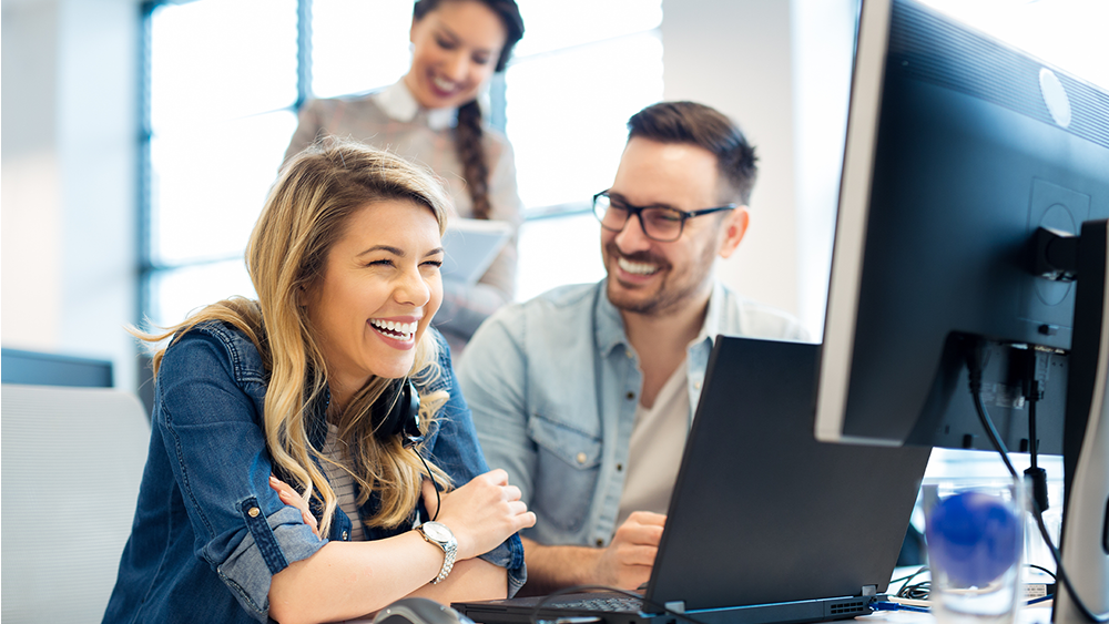 Frau und Mann vor einem Computer am lachen