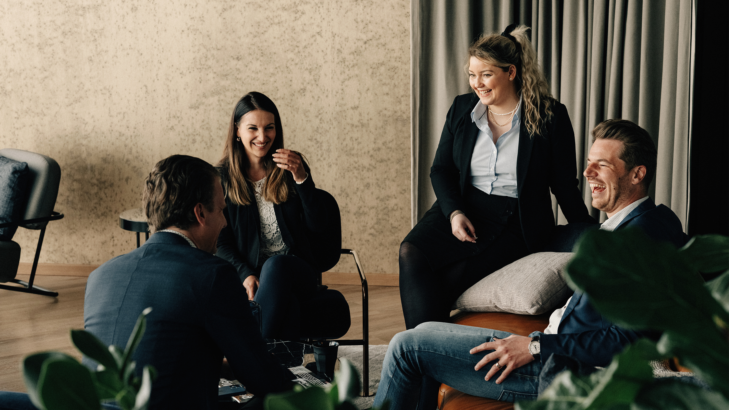 Vier Personen auf einem Sofa lachen sich gegenseitig an
