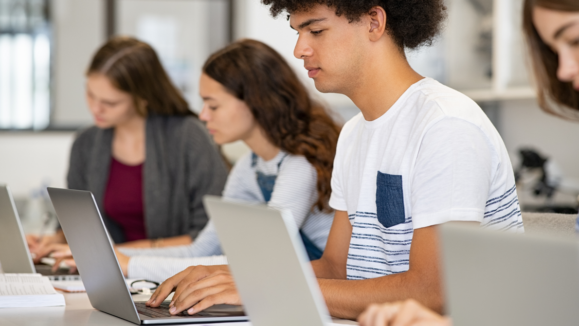 Junge Studenten sitzend im Schulzimmer am Laptop 