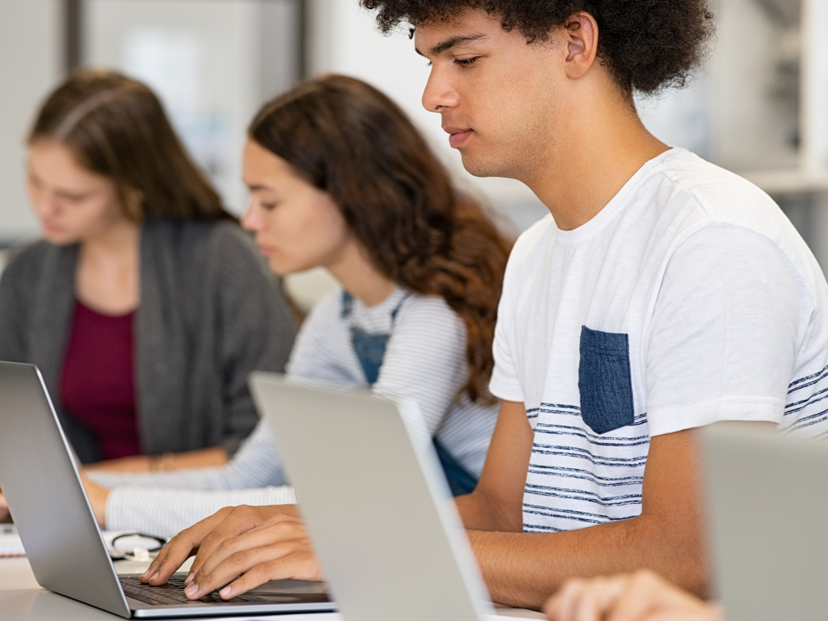 Junge Studenten sitzend im Schulzimmer am Laptop 