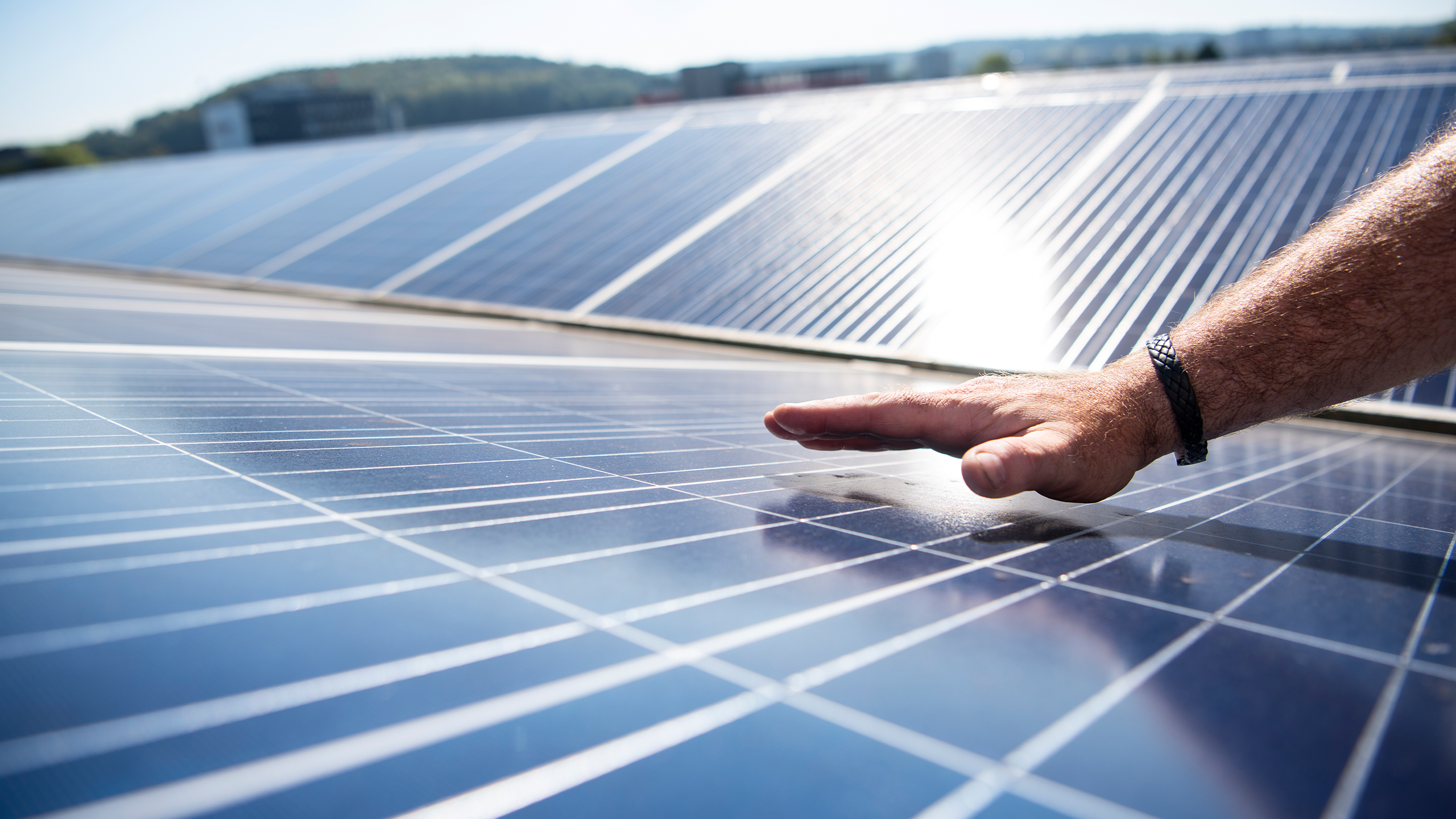 Männliche Hand führt über ein Solarpanel einer Solaranlage