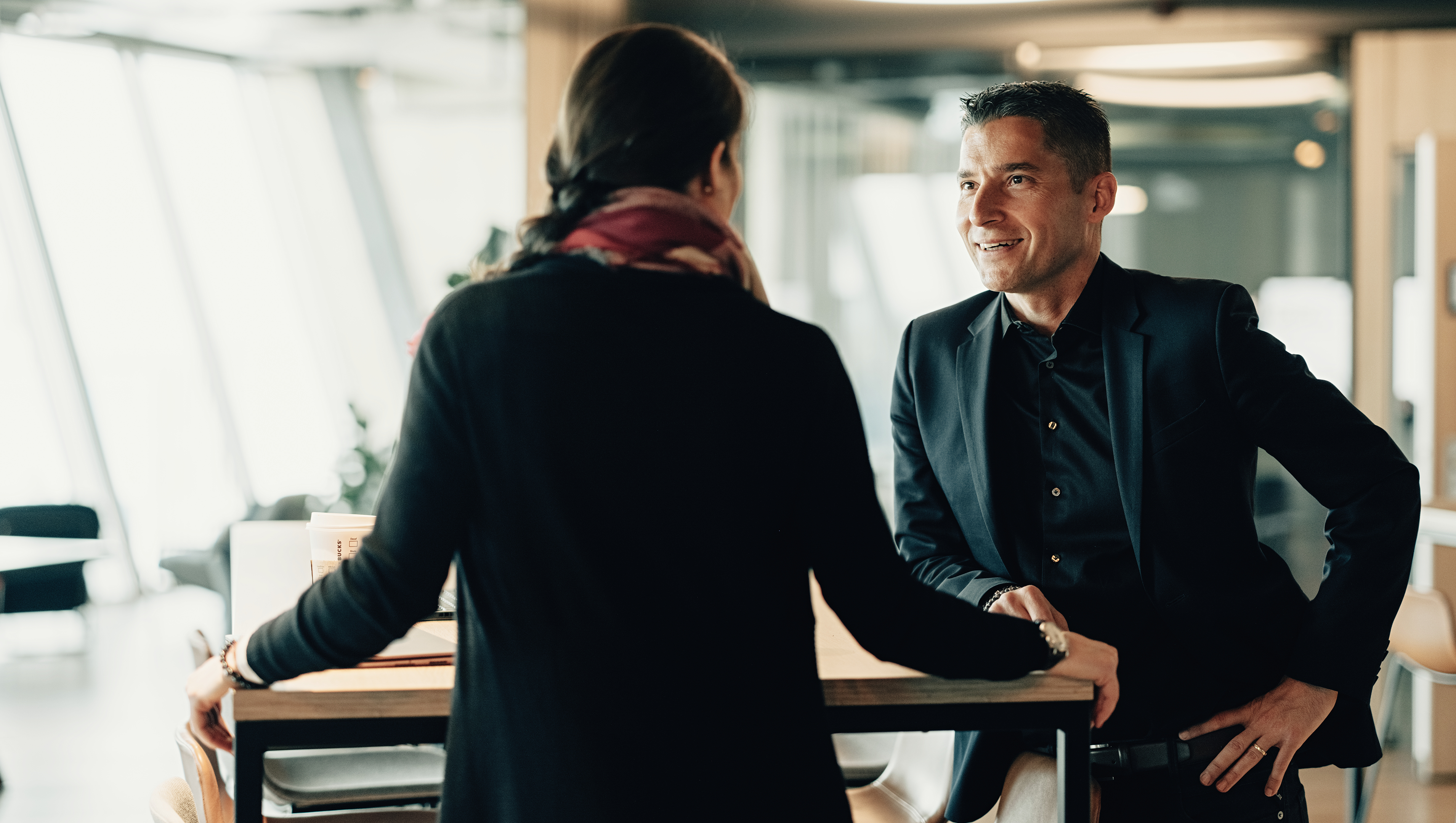Männlicher Business Consultant steht mit Frau an Tisch und spricht