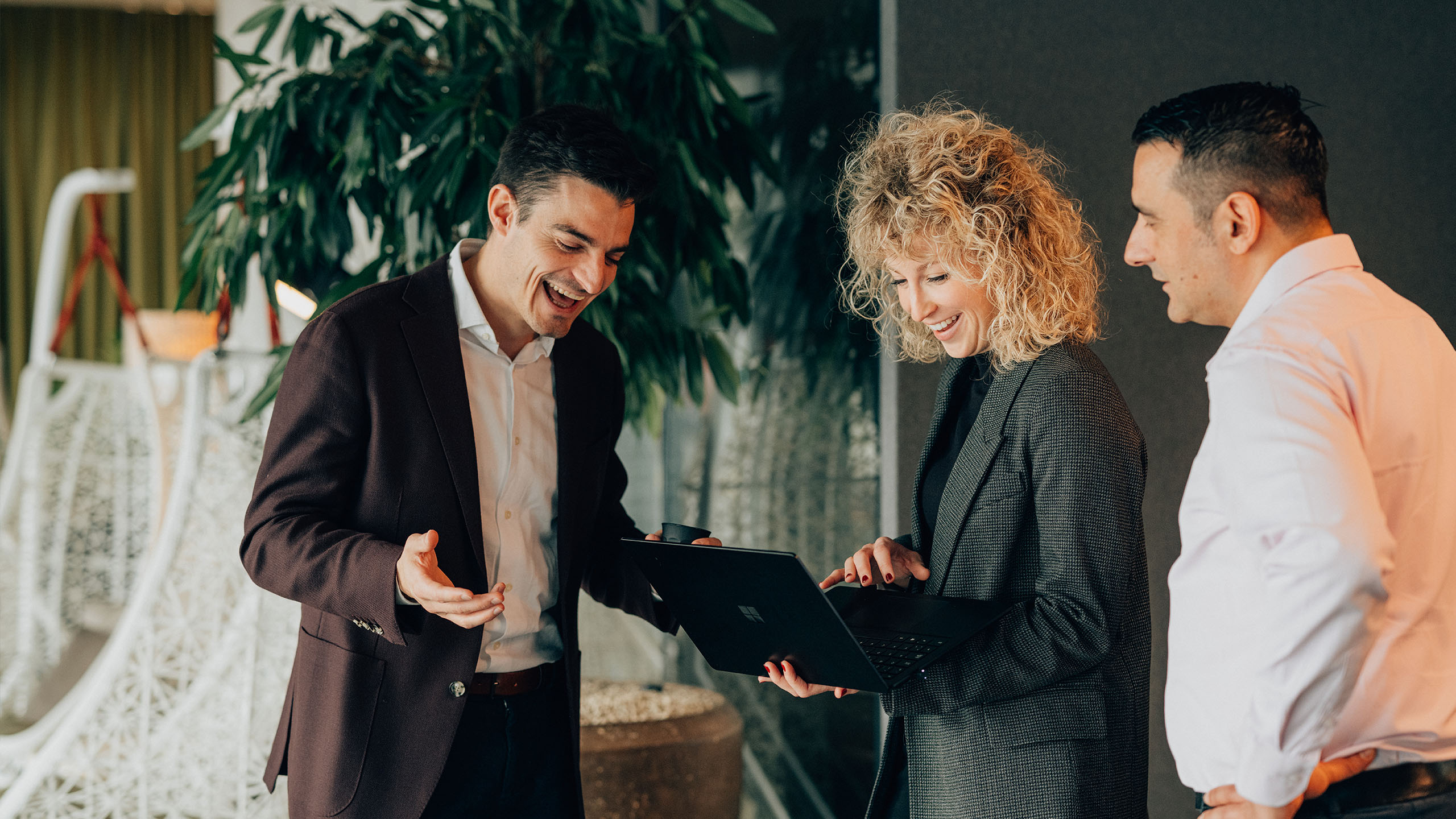 3 Mitarbeitende stehen im Gang an einem Laptop und schauen rein