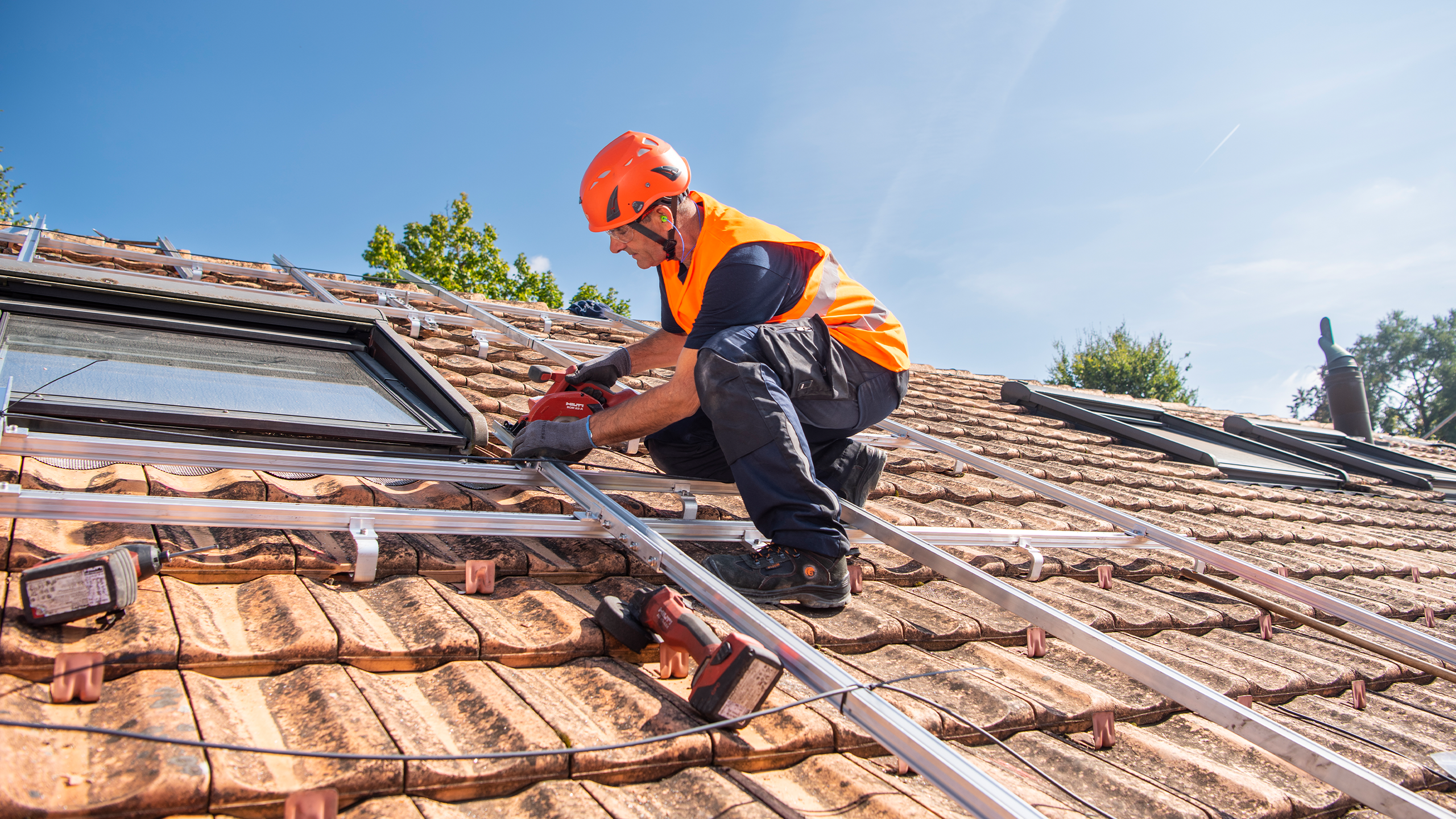 Mann montiert auf einem Dach die Schienen für die Solarpanels