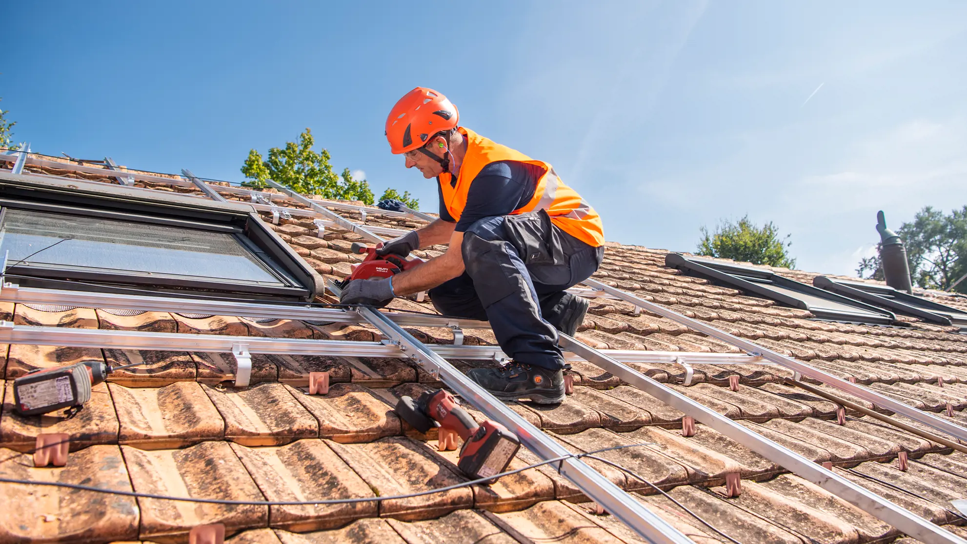 Mann montiert auf einem Dach die Schienen für die Solarpanels
