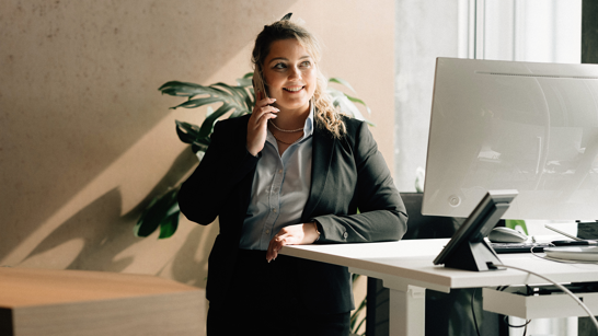 isolutions Whitepaper Change Management Junge Empfangsdame steht bei ihrem Stehtisch und telefoniert