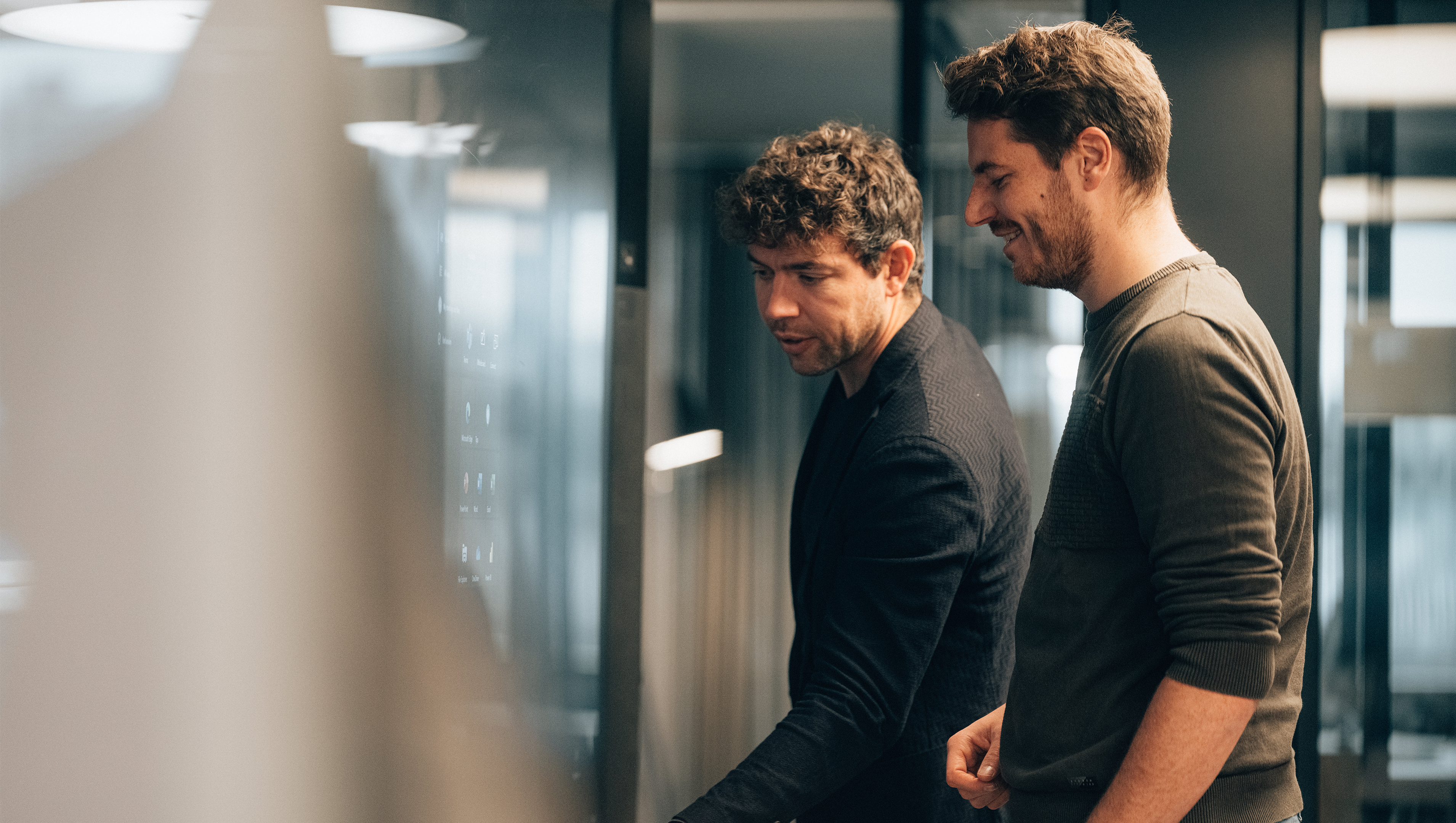 Männlicher Lead M365 Cloud Engineer Operations steht  mit Mann vor Surfacehub