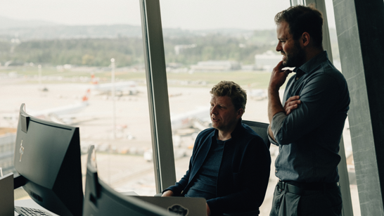 Zwei Männer tauschen sich am Arbeitsplatz aus und schauen dabei in ein Screen