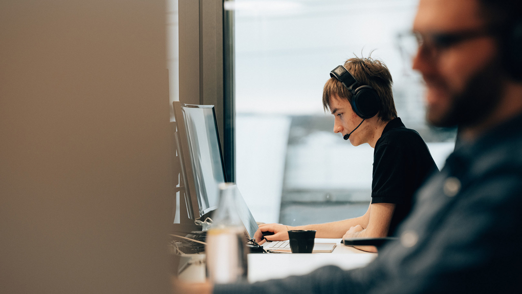 Junger Mann am PC Mit Headset für Beratung