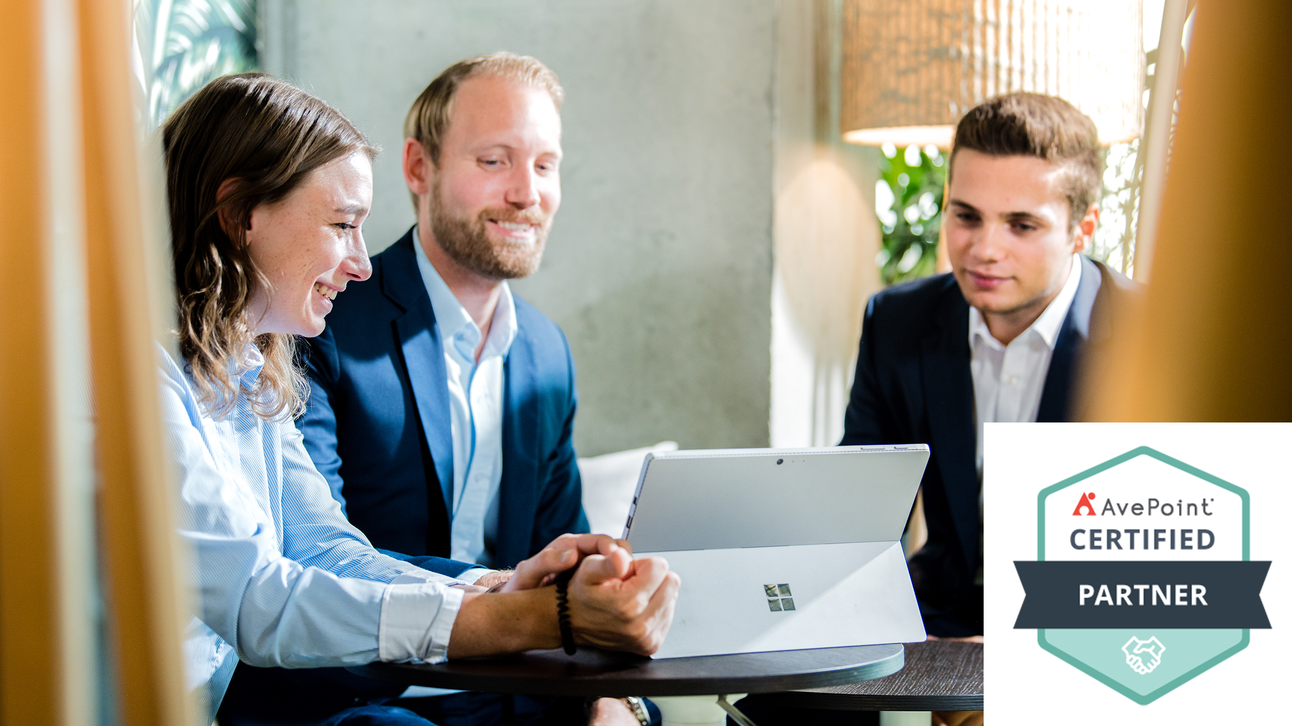 3 Personen Sitzen in einer Lounge um einen Microsoft Surfe PC