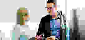 isolutions Academy SharePoint Migration Frau und Mann vor einer grossen Kaffeemaschine