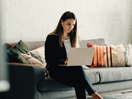 Whitepaper Cloud Operations Frau sitz auf einem Sofa mit dem Laptop auf dem Schoss