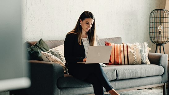 Whitepaper Cloud Operations Frau sitz auf einem Sofa mit dem Laptop auf dem Schoss