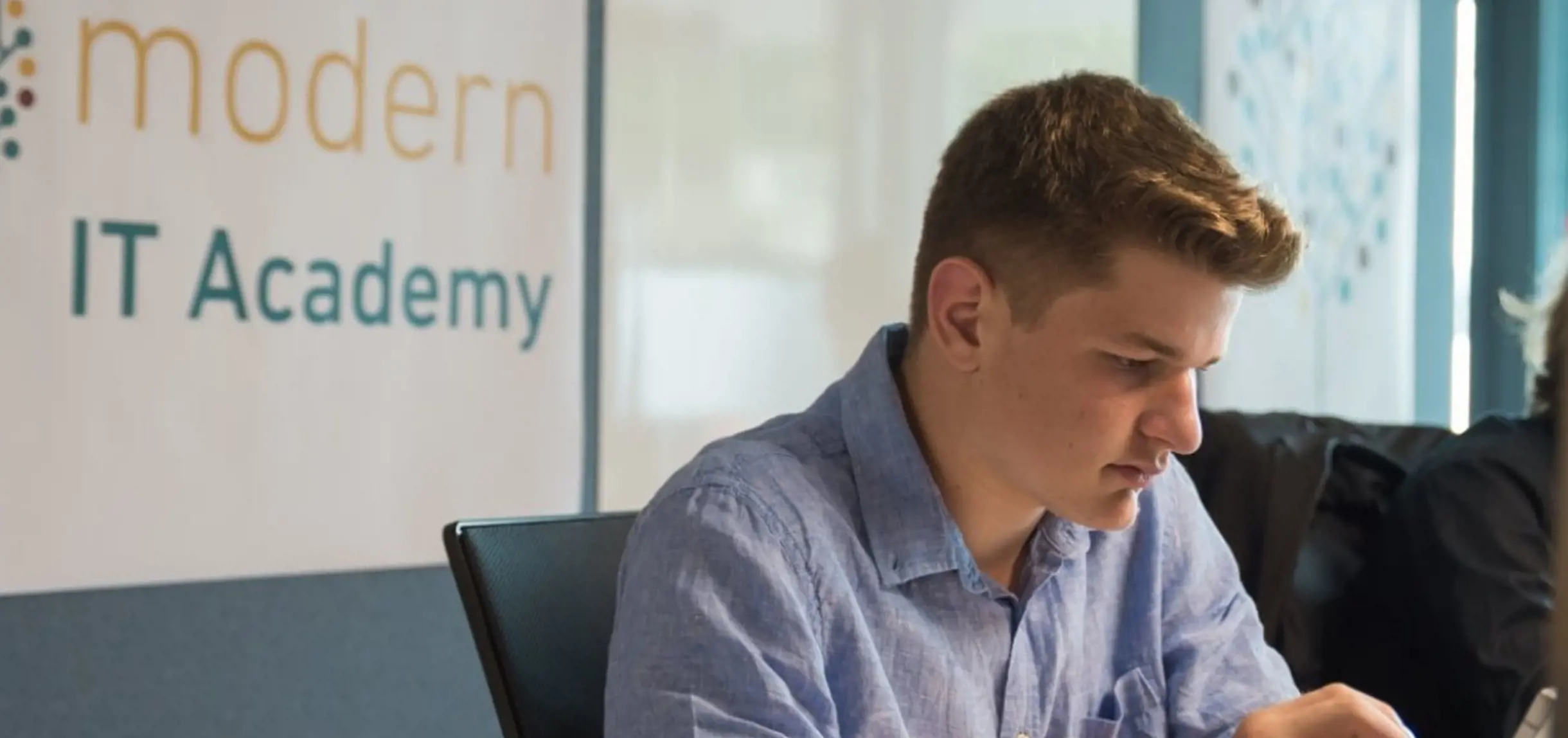 Junger Lehrling im blauen Hemd bei der isolutions Modern IT Academy