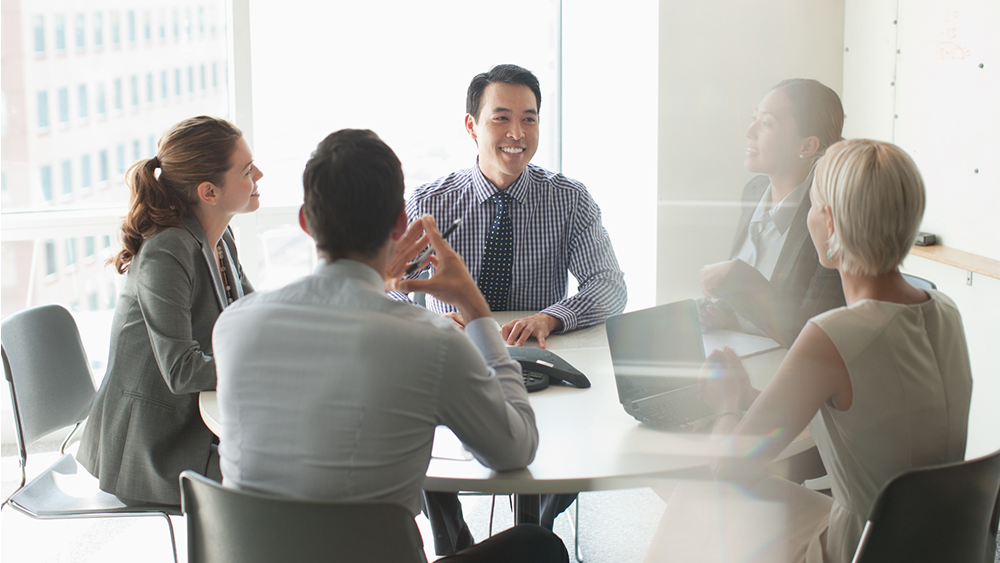 Sitzung an einem runden Tisch in einem Büro mit 5 Personen