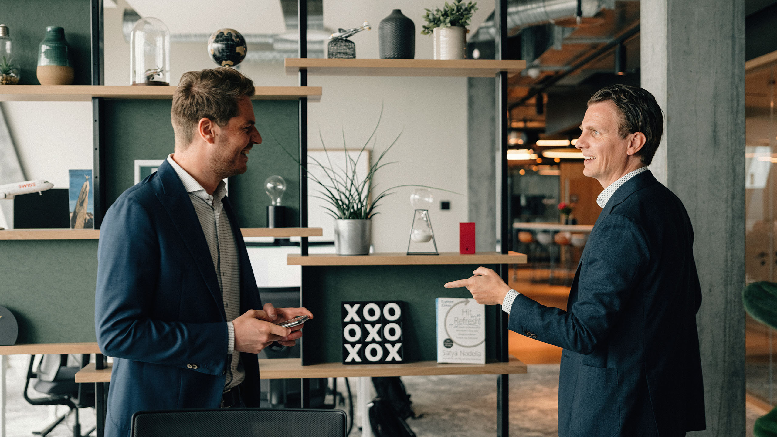 Zwei glückliche Mitarbeitende sprechen zueinander in einem modernen Arbeitsplatz