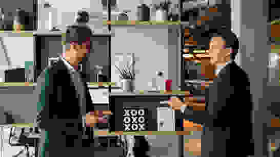 Employee Experience Zwei glückliche Mitarbeitende sprechen zueinander in einem modernen Arbeitsplatz