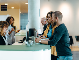 isolutions Whitepaper Public Sector Verwaltungsmitarbeitering bedint ein junges Paar am Schalter