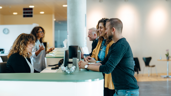 isolutions Whitepaper Public Sector Verwaltungsmitarbeitering bedint ein junges Paar am Schalter