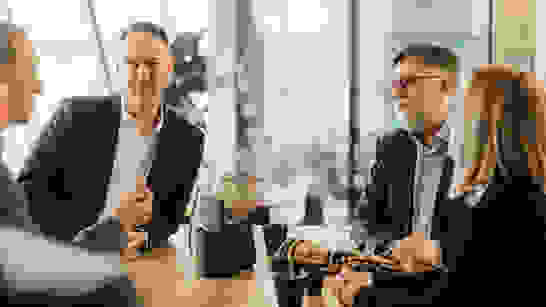 Security Consulting Besprechung von 4 Personen mit Kaffee an einem Hochtisch zu Security Consulting
