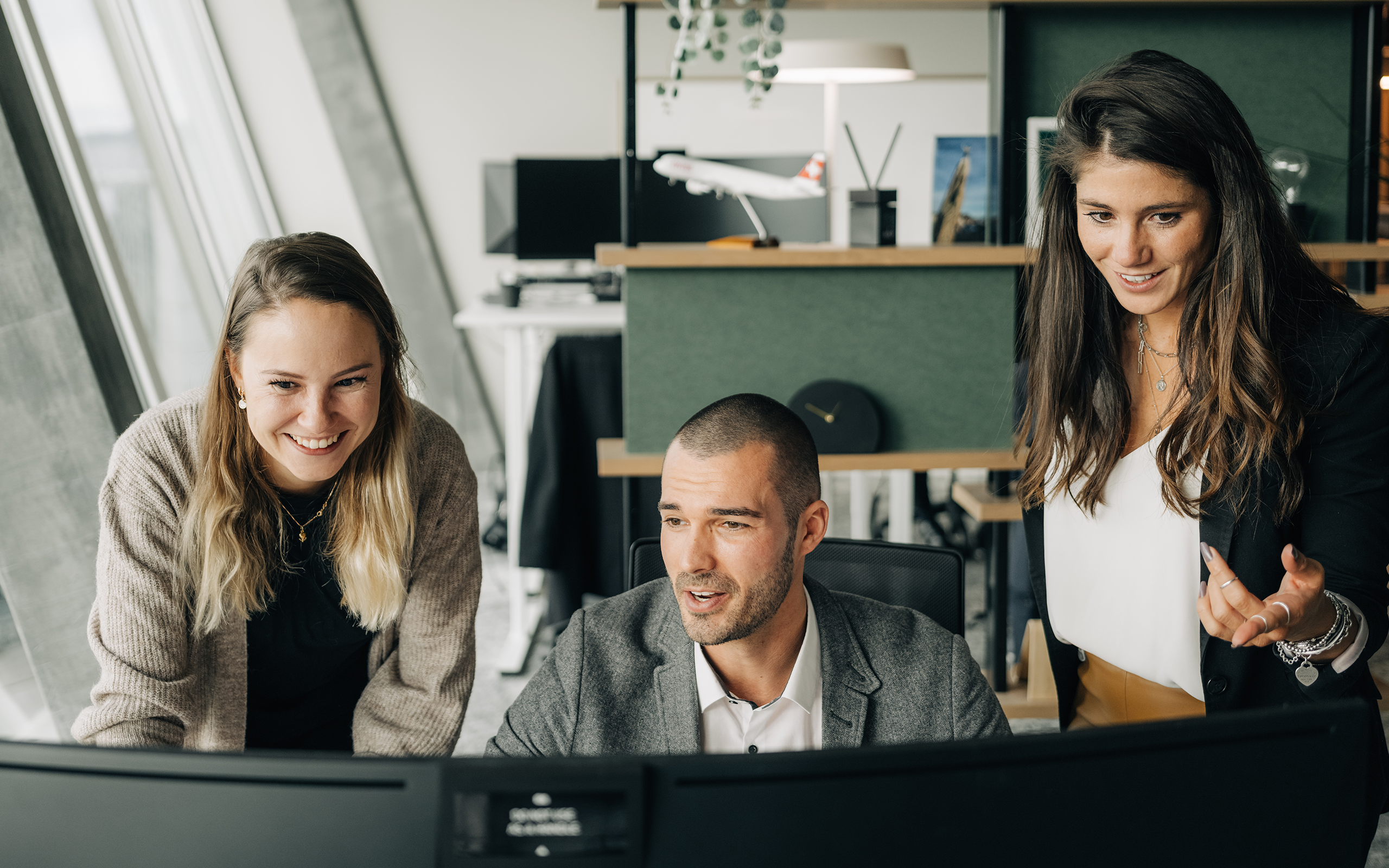 Zwei weibliche und ein männlicher Digital Marketing Manager diskutieren vor PC Bildschirm