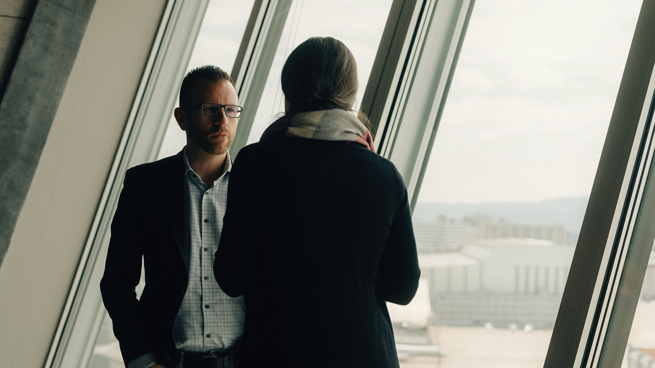 Mann und Frau vor Fensterfront besprechen Angebote für Cloud Services
