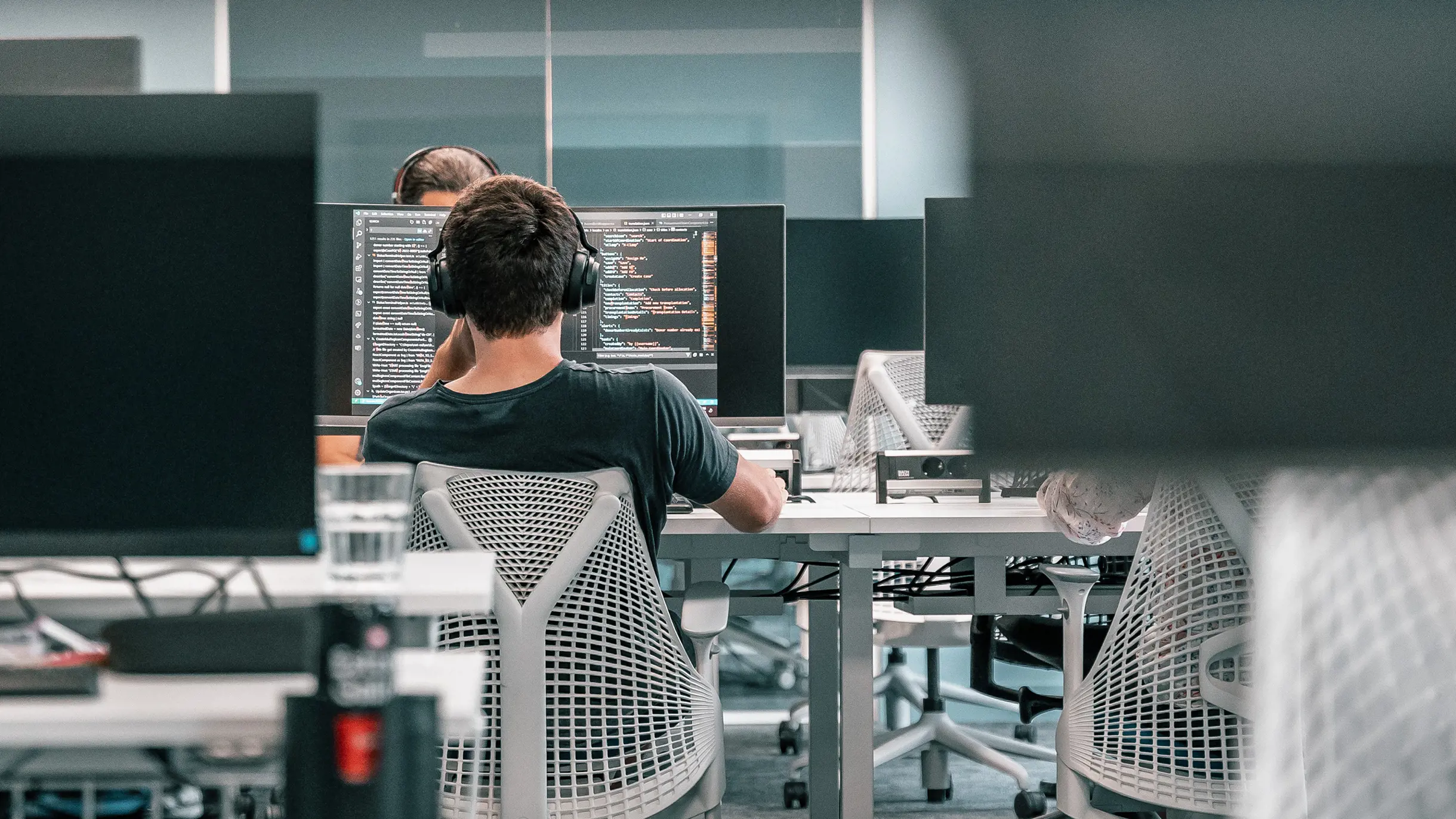 Ein männlicher Azure Engineer sitzt vor Laptop und arbeitet an Code