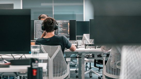 Offene Stelle als Azure Engineer Enterprise Business Ein männlicher Azure Engineer sitzt vor Laptop und arbeitet an Code