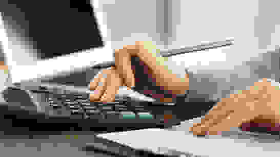 VBV Education Manager Hand die einen Stift hält und etwas in einem Taschenrechner eingibt