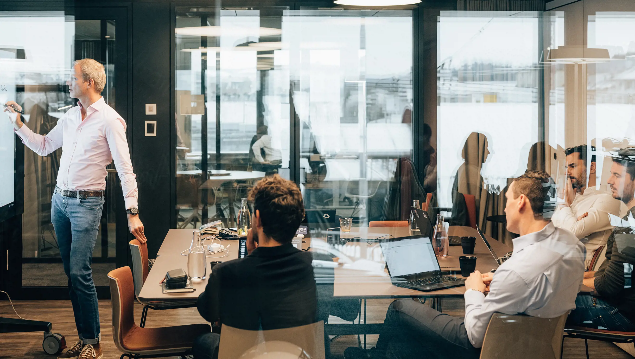 Männlicher Senior Project Manager steht in Sitzungszimmer vor Surfacehub und zeichnet