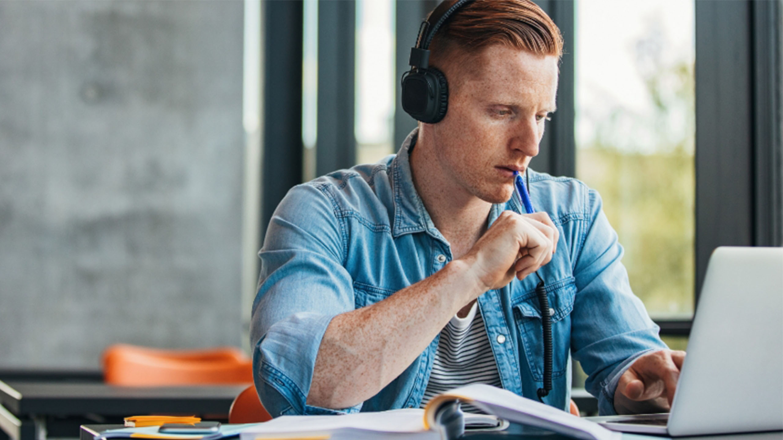 Student am Lernen für Prüfung vor PC mit Headset und Bücher in Lerninstitut