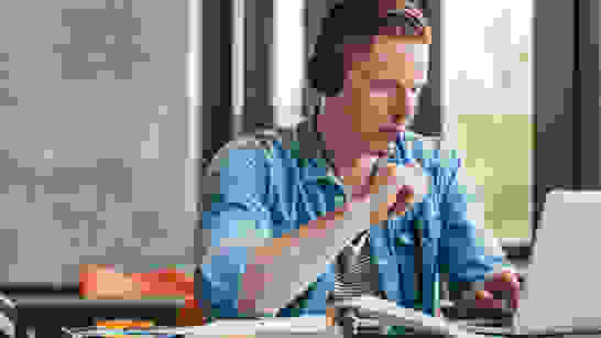 LMS Examiniation Panning Student am Lernen für Prüfung vor PC mit Headset und Bücher in Lerninstitut