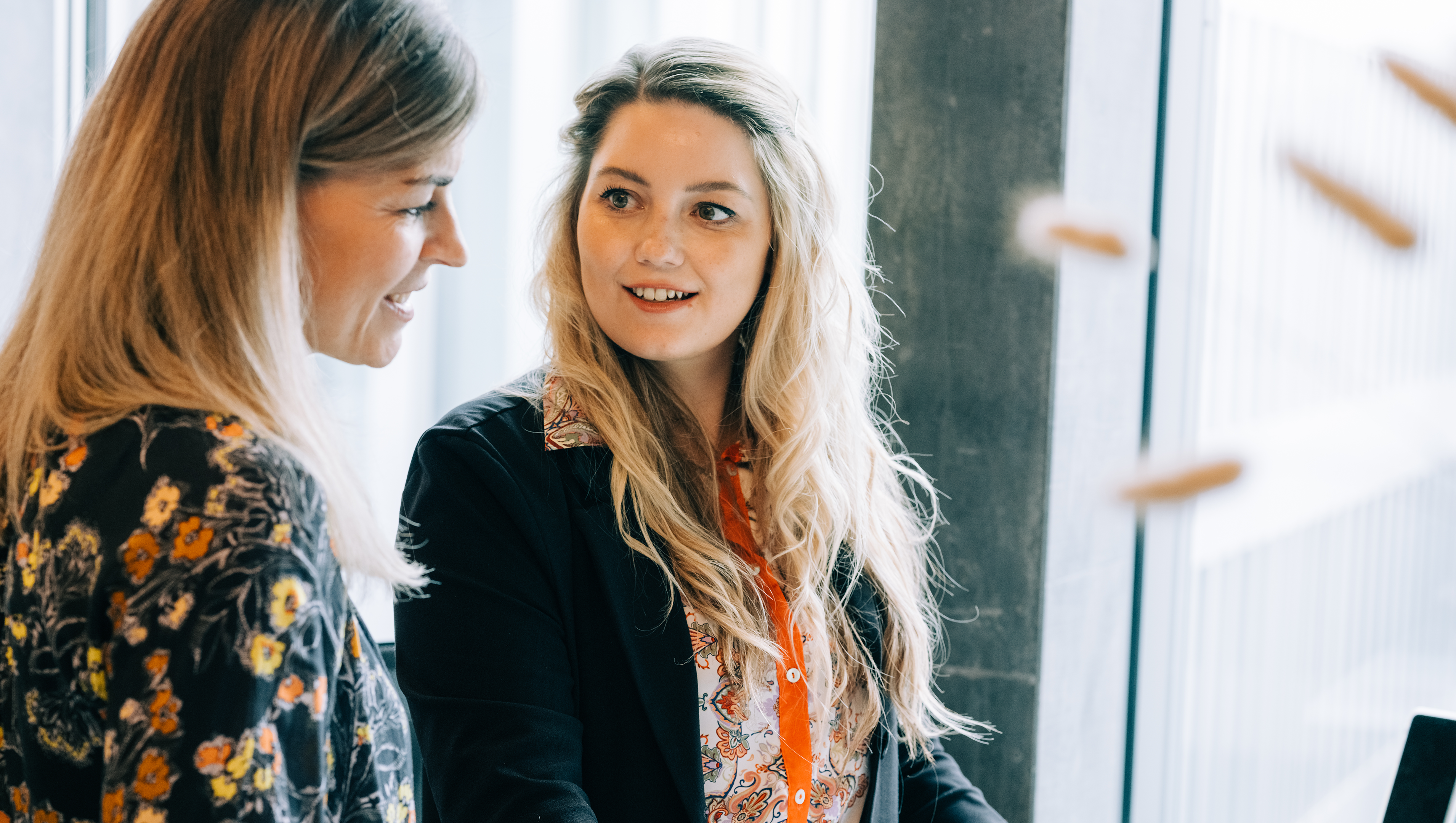 Weibliche ICT Fachperson steht an Arbeitsplatz und spricht mit Frau