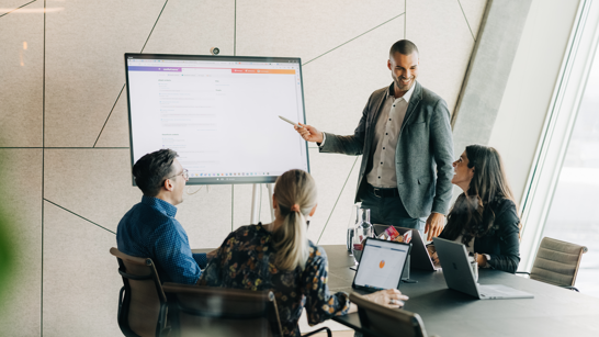 isolutions Whitepaper App Modernization Sitzung mit 4 Personen, eine davon zeigt etwas am Screen