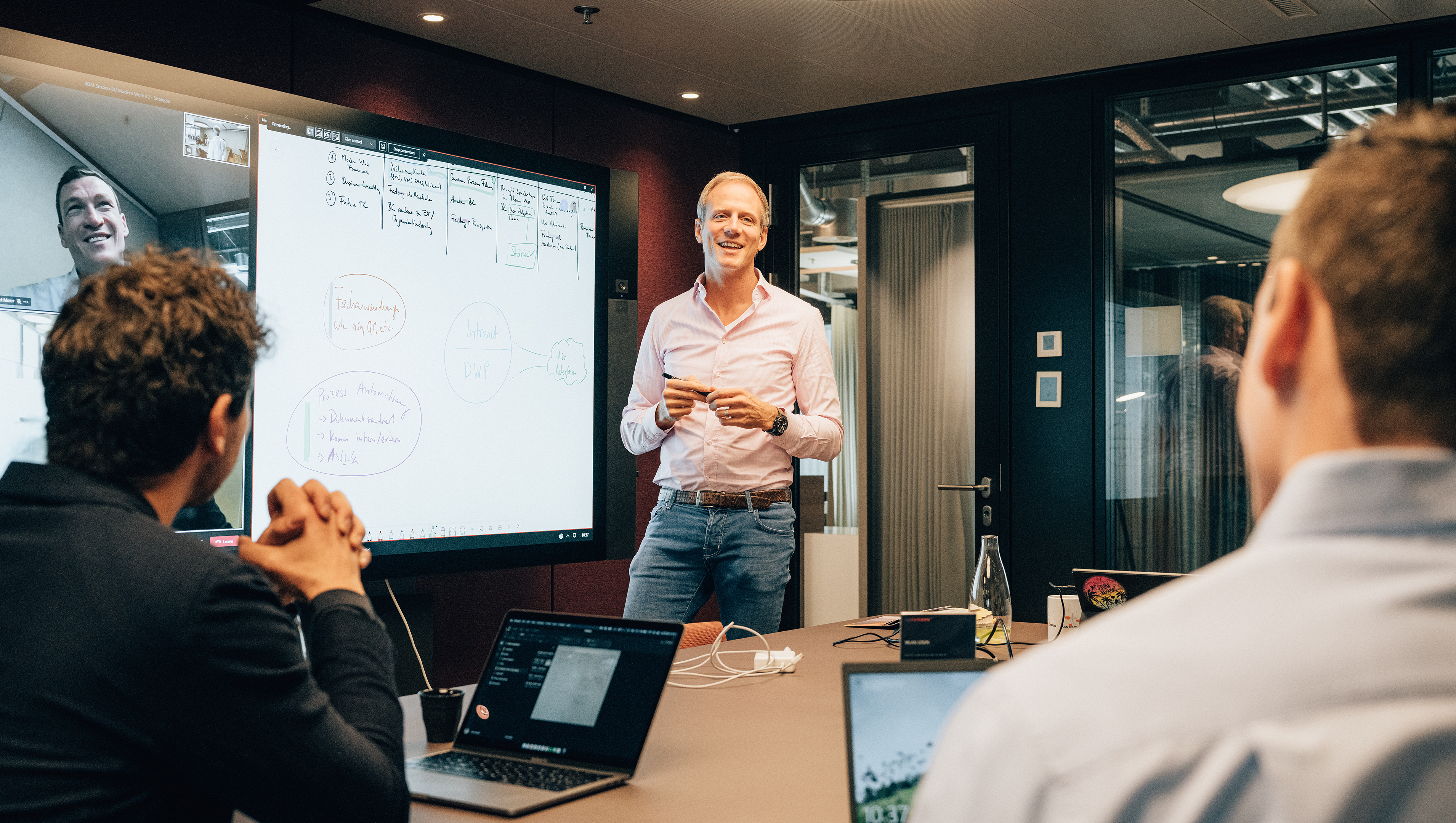 Männlicher Trainer für Business Consultant steht vor Surface Hub in Sitzungszimmer