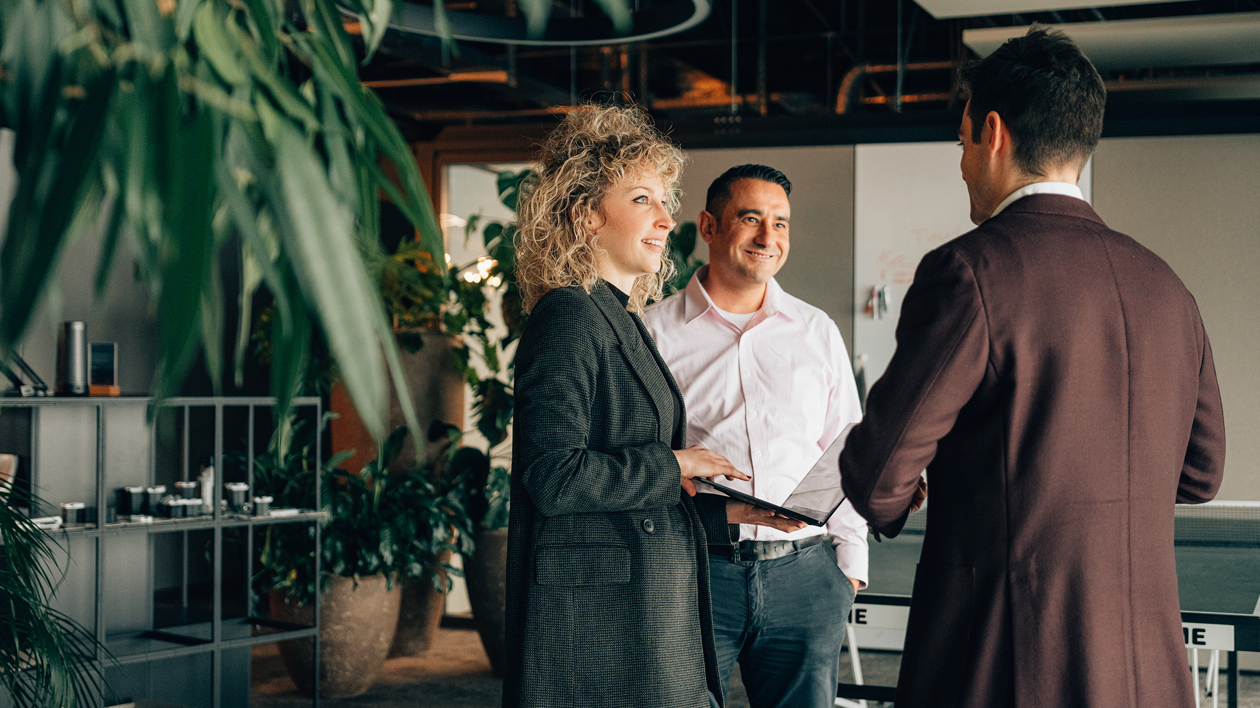 Drei Personen unterhalten sich stehend in einem Grossraumbüro