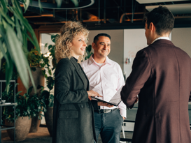 Microsoft Dynamics 365 Lizenzberatung Drei Personen unterhalten sich stehend in einem Grossraumbüro