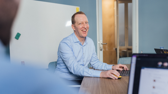 Engineering Manager Man sitting on a meeting room table smiling