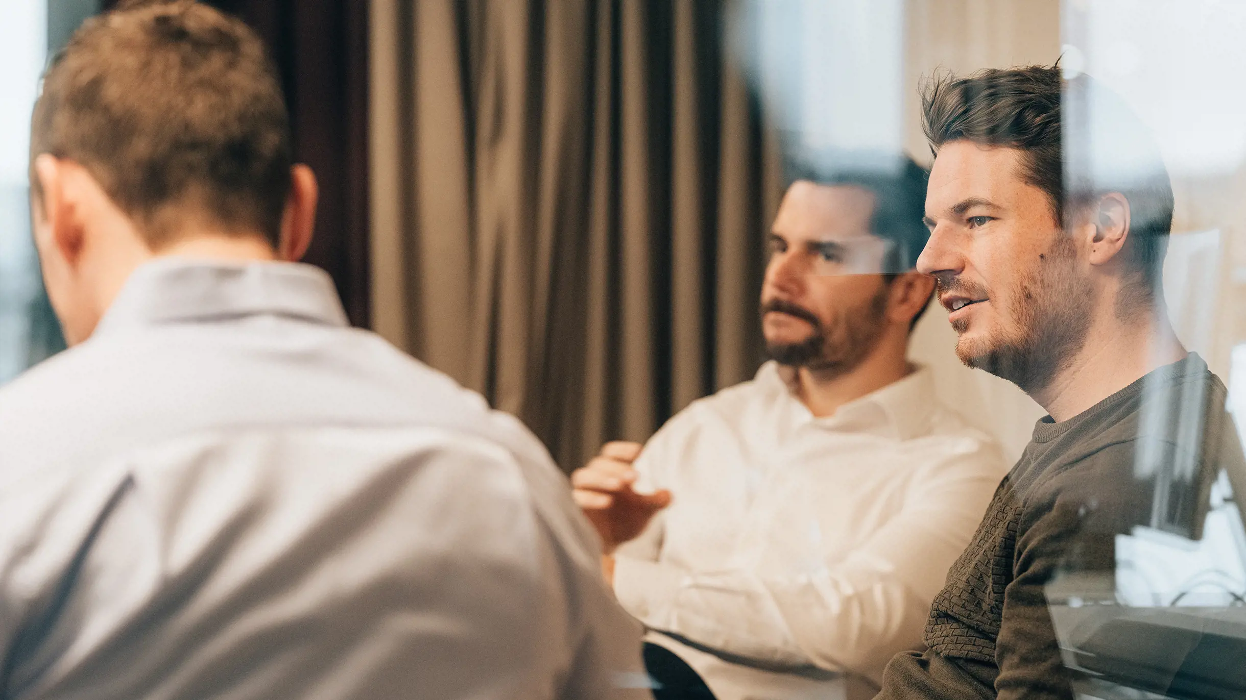 Männlicher Project Manager sitzt mit Männern in Sitzungszimmer 