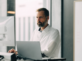 isolutions Whitepaper Workplace as a Service Herr am Arbeitsplatz am arbeiten, schaut konzentriert in PC